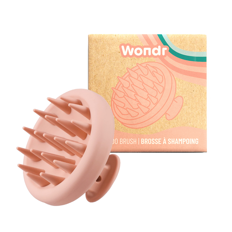 A silicone scalp massager brush with pink bristles, displayed alongside its packaging which has 'Wondr' branding.