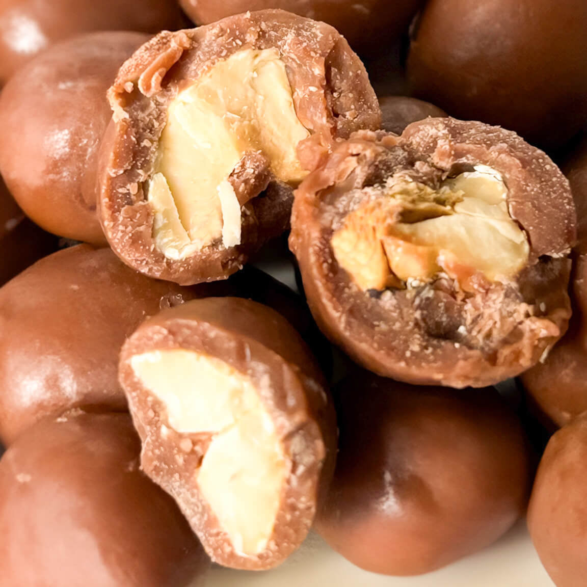 Karü chocolate-covered cashews without packaging, with some split in half revealing the cashew inside.