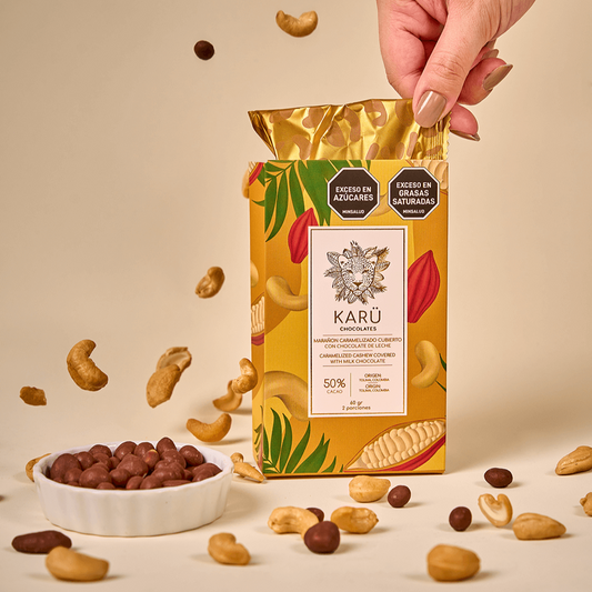 Karu chocolate-covered cashew box, with a hand pulling out the inner pack and floating cashews next to a bowl of the product.